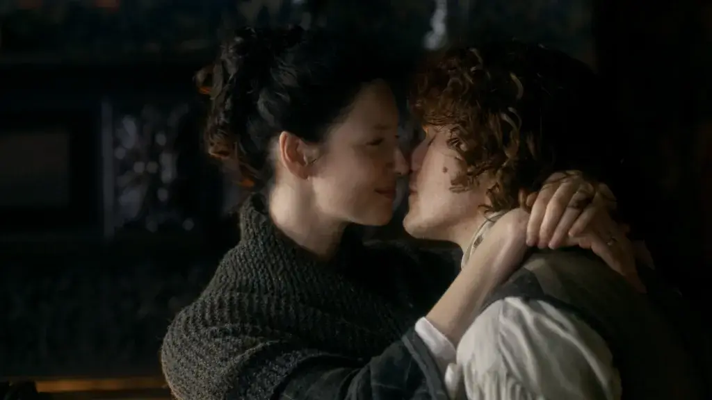 Claire et Jamie s’embrassent tendrement à Lallybroch, moment de complicité emblématique de leur relation dans Outlander.