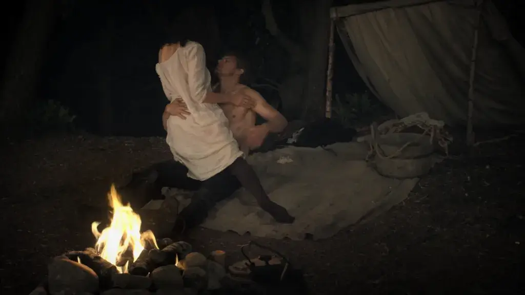 Jamie Fraser et Claire Randall partagent un moment d’amour près d’un feu, sous les étoiles, dans une scène romantique de la série Outlander. - Saison 4