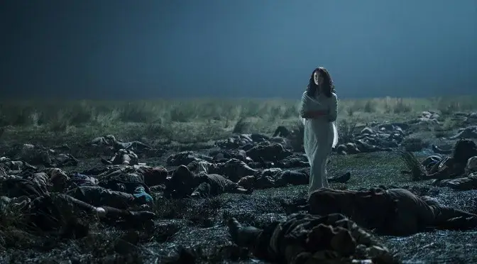 Claire Fraser en robe blanche au milieu du champ de bataille de Culloden, entourée de corps, dans une scène onirique marquante d'Outlander.